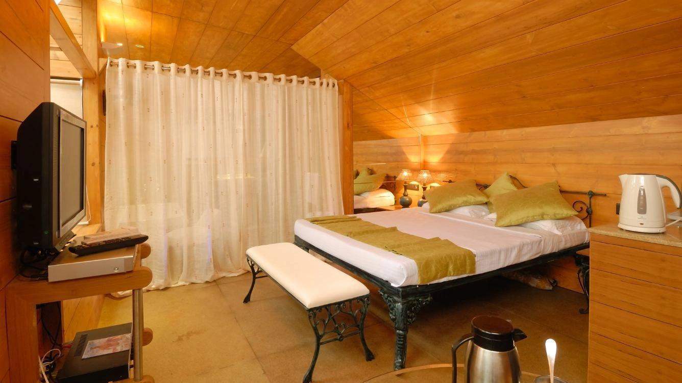 Cozy bedroom with wooden paneling and soft lighting at Ramsukh Resort in Mahabaleshwar.